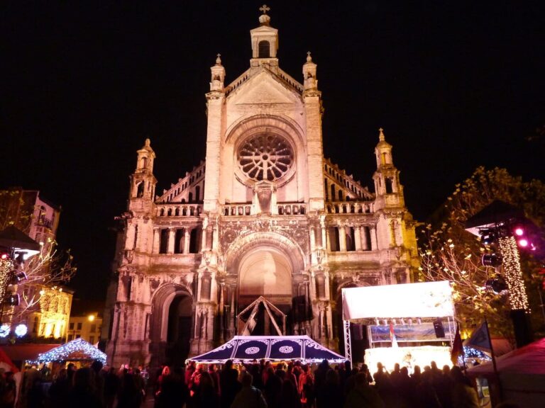 L’église Sainte-Catherine illuminée au-dessus des chalets et d’une scène du marché, la nuit
