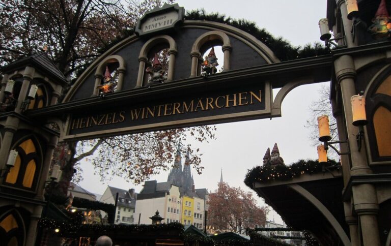 L’arche d’entrée en bois sculpté du marché Heinzels Wintermärchen, avec les flèches de la cathédrale au loin