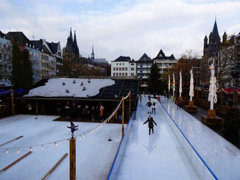 Le chemin de glace du Heumarkt entre les chalets, avec les flèches de la cathédrale à l’horizon
