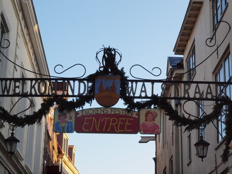 Arche de fer forgé et guirlande de sapin à l’entrée de la Walstraat, avec le panneau « Entree » du Dickens Festijn