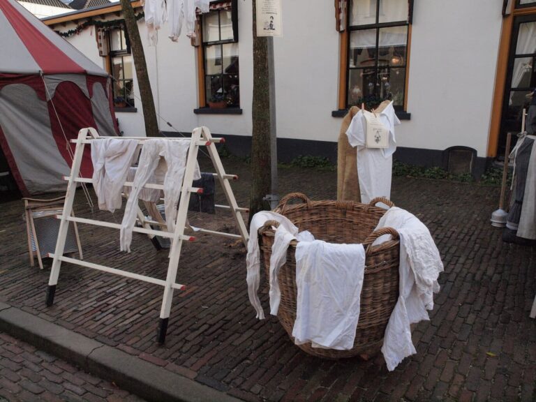 Décor de lavoir victorien avec séchoir à linge et panier en osier dans une rue pavée du Dickens Festijn