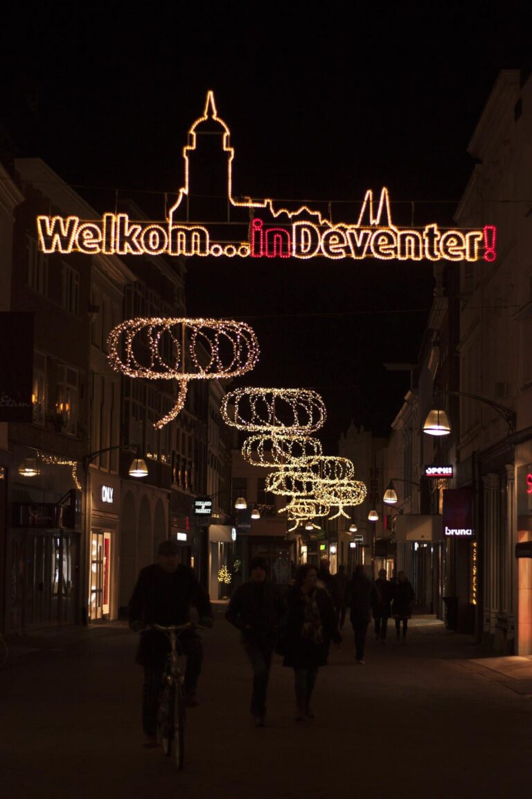 Rue piétonne de Deventer la nuit, sous les guirlandes lumineuses et l’enseigne « Welkom in Deventer »