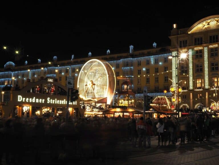 La grande roue illuminée et l’enseigne du Dresdner Striezelmarkt devant les façades éclairées de l’Altmarkt