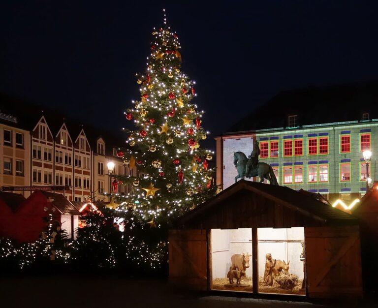 Le sapin décoré de boules rouges, la statue équestre de l’électeur Jean-Guillaume et une crèche dans un abri en bois, sur le Marktplatz, la nuit