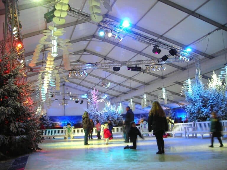 Patineurs sur la patinoire couverte d’Efteling, décorée de sapins blancs et de lumières bleues