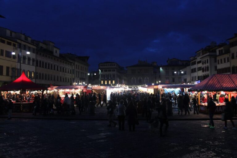 Les stands illuminés du marché de Noël sur la piazza Santa Croce à la tombée de la nuit, entourés des palais de la place
