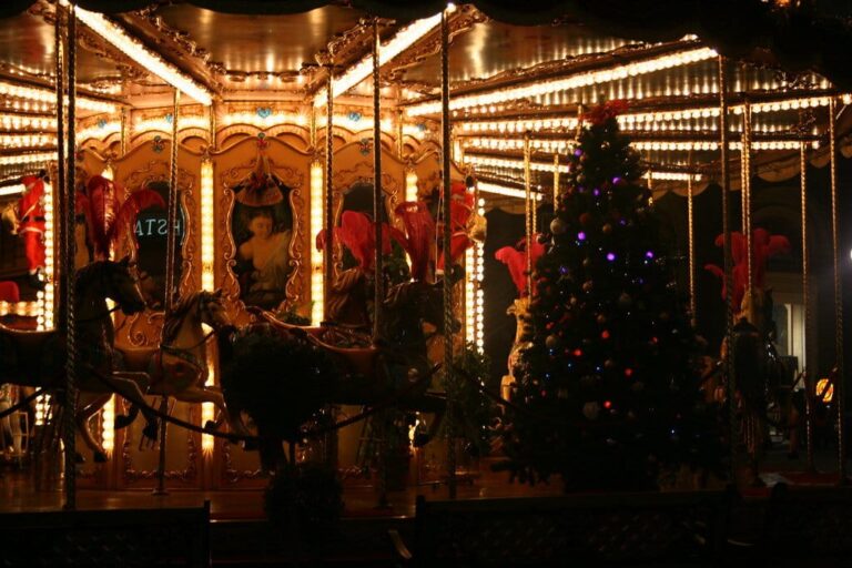 Le manège ancien de la piazza della Repubblica illuminé la nuit, avec un sapin décoré à côté des chevaux de bois