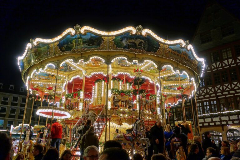 Manège à étage illuminé du marché de Noël, devant une maison à colombages du Römerberg, la nuit