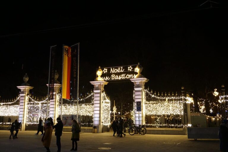 Grilles du parc des Bastions couvertes de guirlandes lumineuses, sous l’enseigne « Noël aux Bastions »