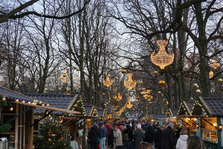 Allée de chalets de bois et de sapins décorés sous les lustres lumineux de la promenade des Bastions, un matin de décembre