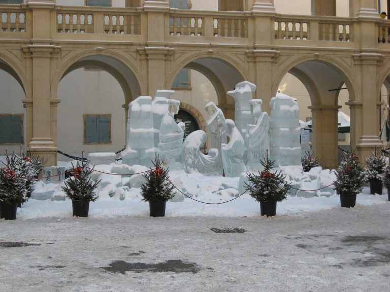 Personnages de la crèche de glace sous la neige, dans la cour du Landhaus de Graz, bordée de petits sapins décorés