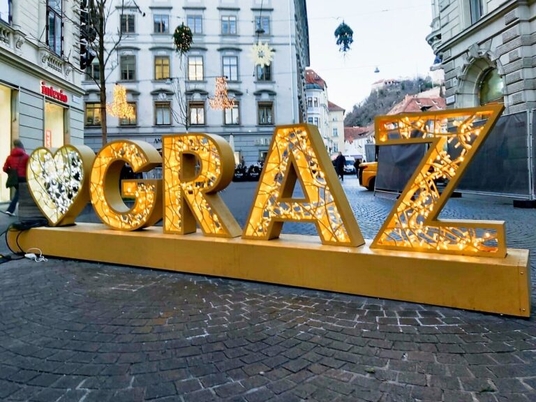 Lettres lumineuses GRAZ à l’entrée de la Schmiedgasse, rue ornée de suspensions de branchages pour les fêtes, en direction du Hauptplatz