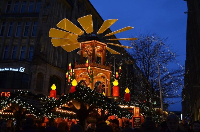 Une grande pyramide de Noël en bois aux pales dorées et aux bougies géantes, au-dessus des stands d’un marché du centre de Hambourg