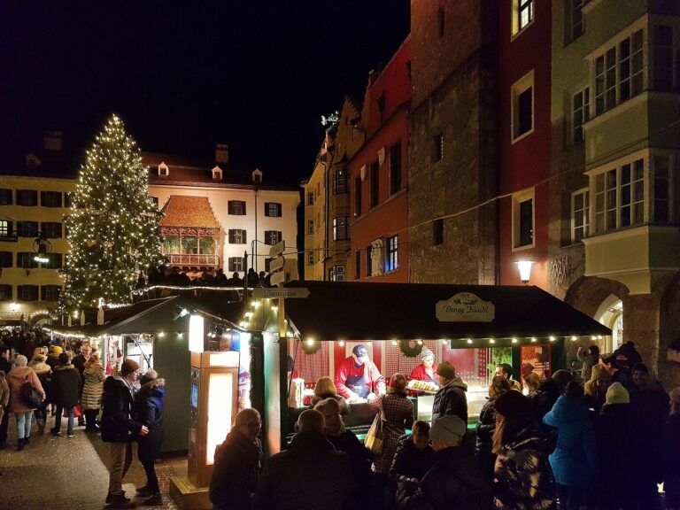 Chalets du marché de Noël entre les maisons colorées de la vieille ville d’Innsbruck, avec le sapin et le Petit Toit d’or au fond, la nuit