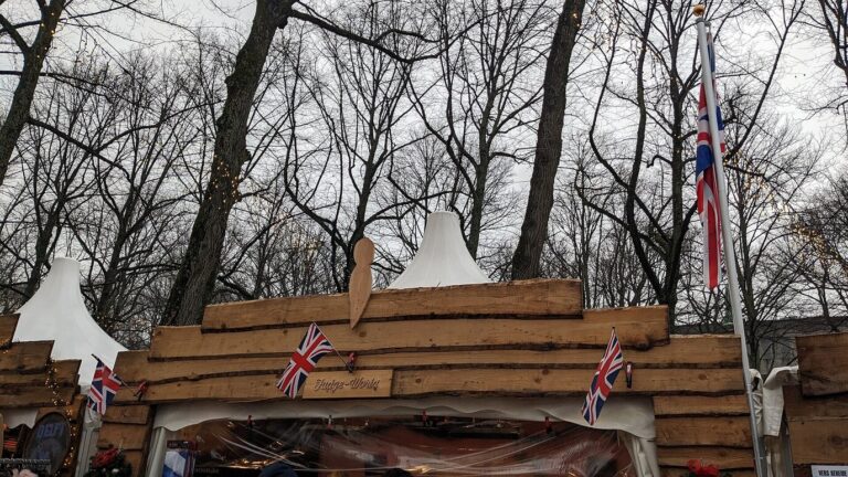 Toit d’un chalet de bois orné de petits drapeaux britanniques, sous les branches nues du Lange Voorhout