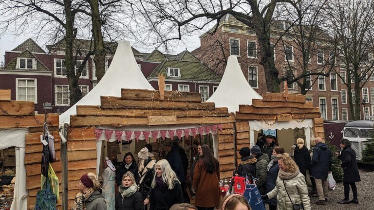 Chalets de la Royal Christmas Fair coiffés de tentes blanches, devant les maisons de brique du Lange Voorhout