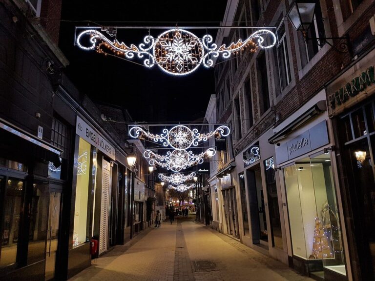 Rue commerçante piétonne du centre de Liège, la nuit, sous des motifs lumineux de Noël en forme de flocons