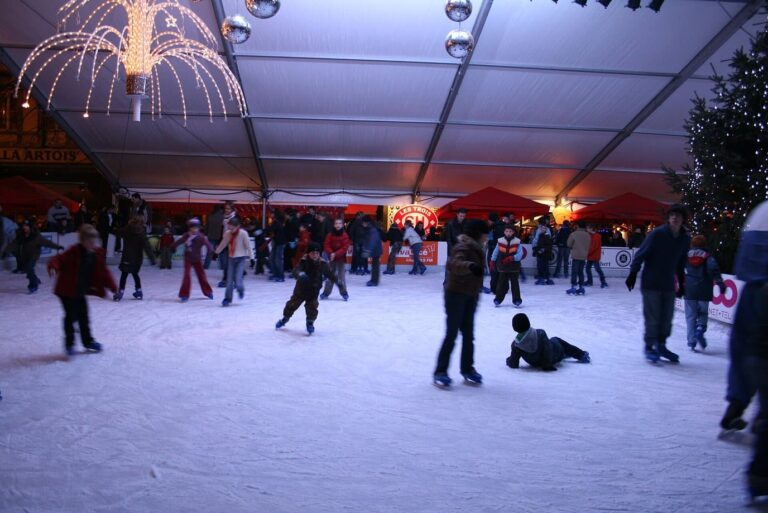 Patineurs sur la patinoire couverte de la place de la Cathédrale, sous un lustre lumineux, avec un sapin illuminé à droite