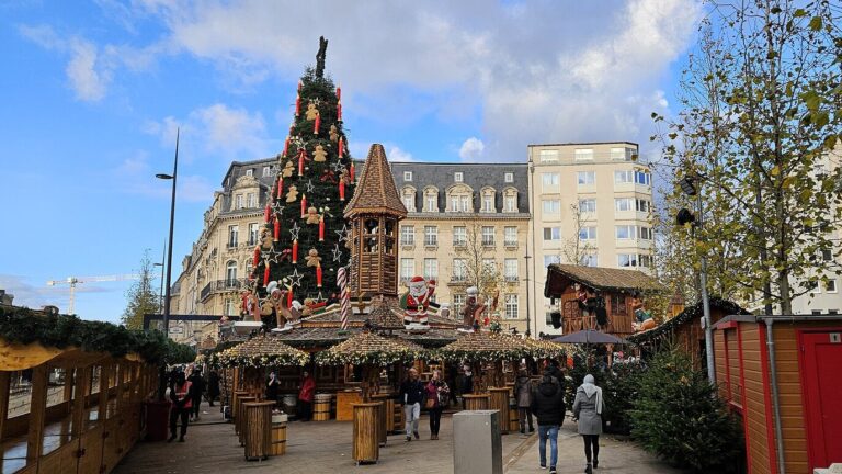 Grand sapin décoré de rubans rouges au-dessus des chalets du Niklosmaart, place de Paris à Luxembourg
