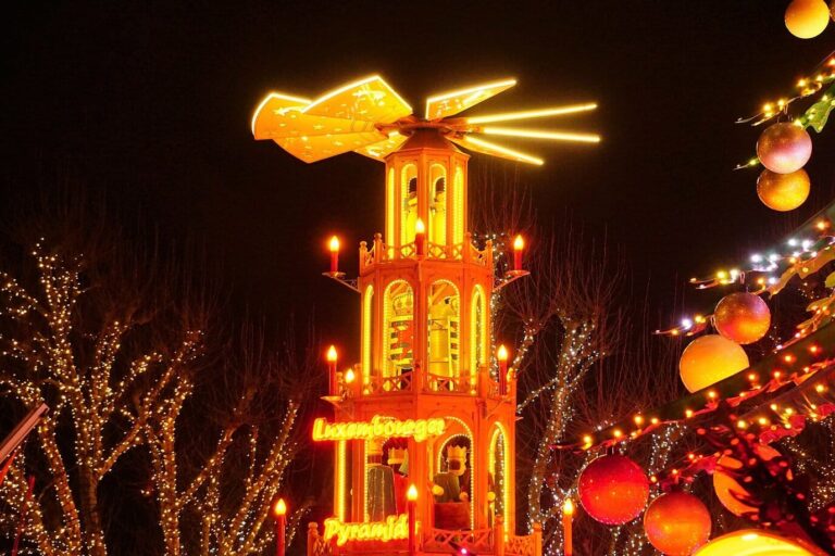 Pyramide de Noël illuminée parmi les arbres couverts de lumières, au marché de la place de la Constitution
