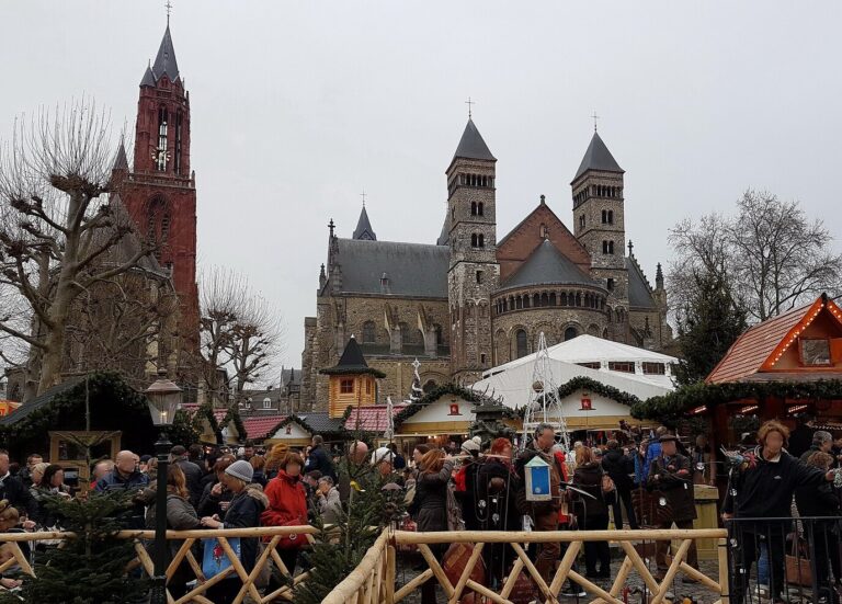Chalets de bois décorés de sapins au marché de Noël du Vrijthof, devant l’église Saint-Jean et la basilique Saint-Servais