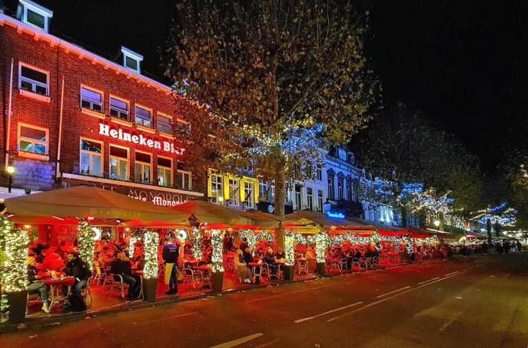 Terrasses des cafés du Vrijthof décorées de sapins et de guirlandes lumineuses, un soir de décembre