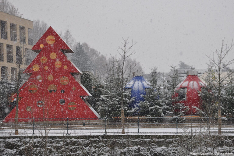 Sapin géant rouge et grandes boules de Noël décoratives près des thermes de Merano, sous la neige