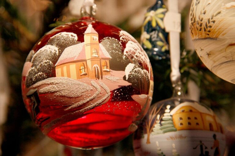 Boule de Noël en verre peinte d’une église sous la neige, en vente sur un stand du marché de Merano