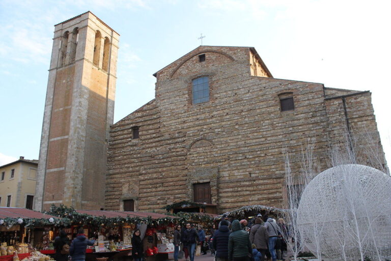 Chalets du marché de Noël et grande sphère lumineuse blanche au pied de la façade de pierre brute et du clocher de la cathédrale de Montepulciano