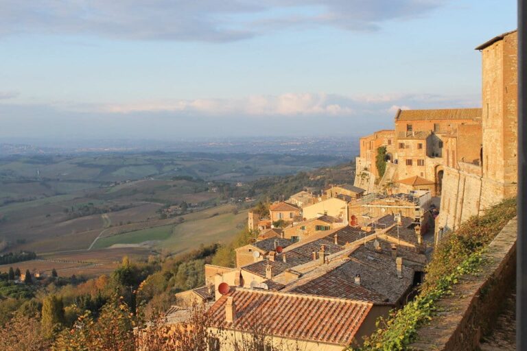 Les toits de Montepulciano accrochés à la crête et la plaine du Valdichiana sous la lumière dorée de fin d’après-midi