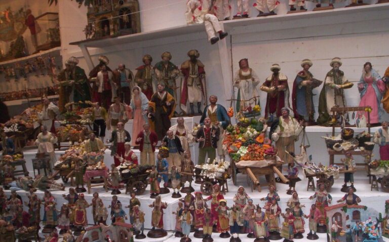 Étagères chargées de santons napolitains : bergers, marchands, rois mages et étals miniatures de fruits et légumes