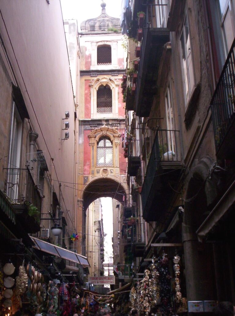 Étals de crèches et de décorations suspendues au pied du campanile rose de San Gregorio Armeno, dans la ruelle