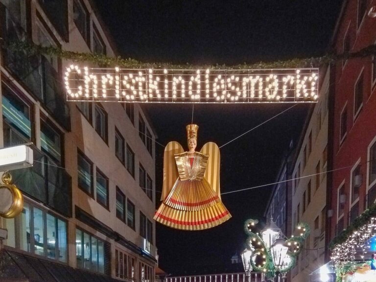 L’enseigne lumineuse « Christkindlesmarkt » et un grand ange doré suspendus au-dessus d’une rue de la vieille ville, la nuit