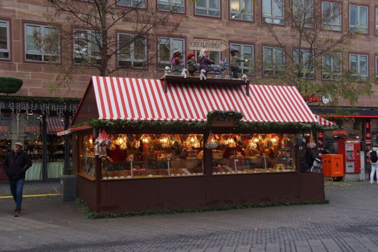 Un chalet à toit rayé rouge et blanc, garni de guirlandes et de figurines, sur le marché de Nuremberg