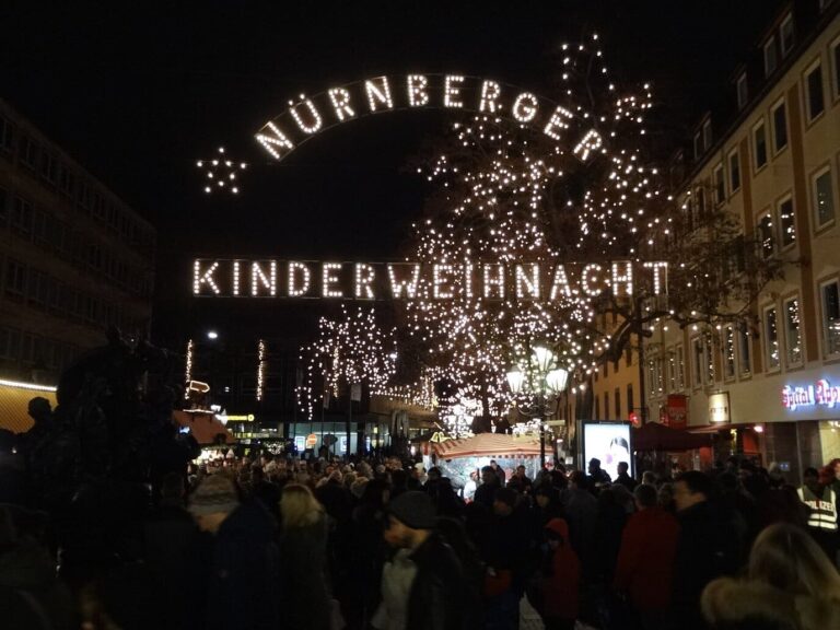 L’enseigne lumineuse « Nürnberger Kinderweihnacht », le marché des enfants, au-dessus des arbres illuminés, la nuit