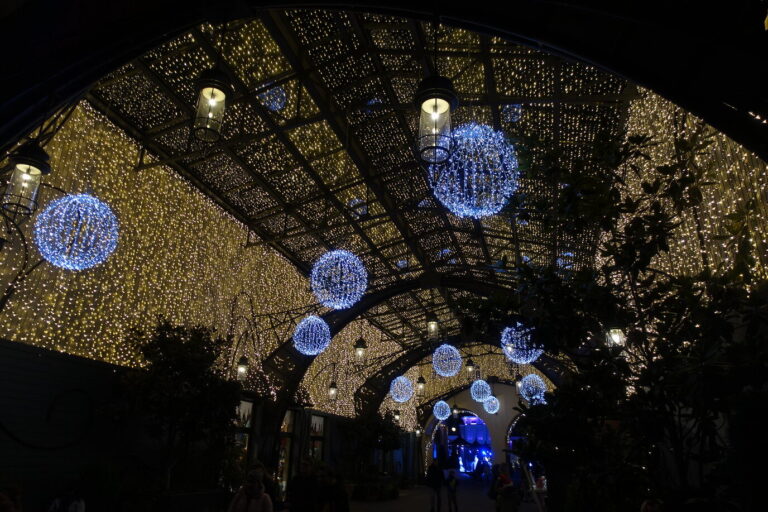 Une allée couverte de guirlandes lumineuses dorées, ponctuée de grosses boules lumineuses