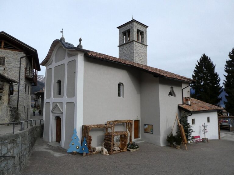 Église de l’Annonciation de Rango et son clocher, une crèche de bois et des sapins décoratifs devant la façade