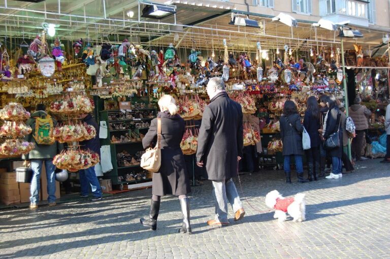 Promeneurs de dos devant un grand stand de décorations de Noël sur la piazza Navona, en plein jour