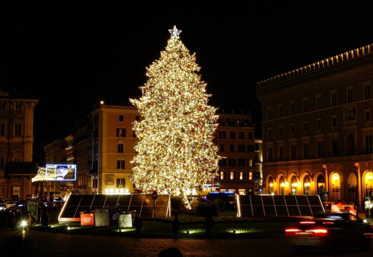Le grand sapin de Noël illuminé de la piazza Venezia la nuit, entre les palais éclairés
