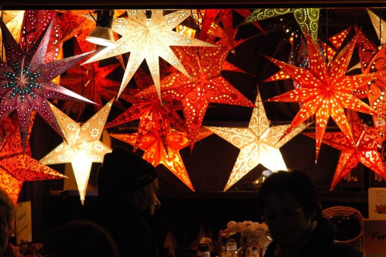 Étoiles en papier lumineuses rouges et blanches suspendues au-dessus d’un chalet du marché de Noël de Salzbourg