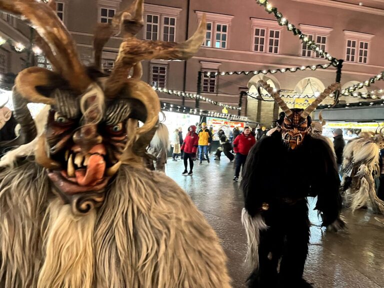 Krampus masqués et couverts de fourrure déambulant entre les chalets du marché de Noël de Salzbourg