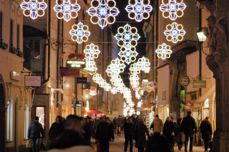 Rue commerçante de la vieille ville de Salzbourg sous des décorations lumineuses en forme de flocons, au début de la soirée