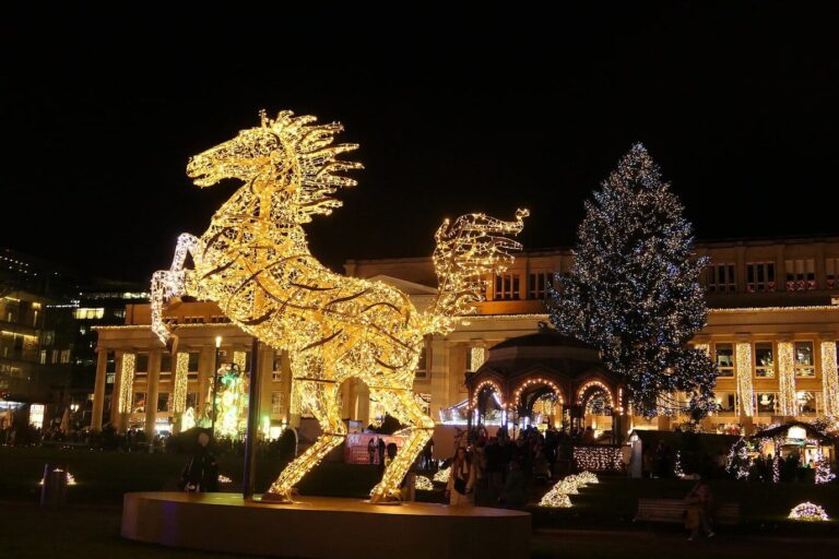 Grand cheval lumineux doré et sapin illuminé devant le Königsbau, sur la Schlossplatz de Stuttgart, la nuit