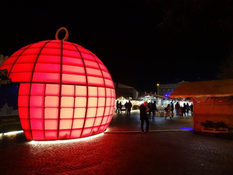 Boule de Noël géante rouge illuminée au milieu des allées du marché, la nuit