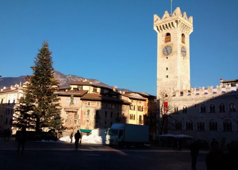 Grand sapin de Noël et Torre Civica sur la piazza Duomo de Trente, sous un ciel d’hiver bleu