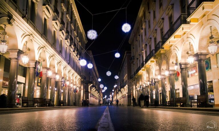 Sphères lumineuses suspendues au-dessus d’une rue à arcades du centre de Turin, la nuit