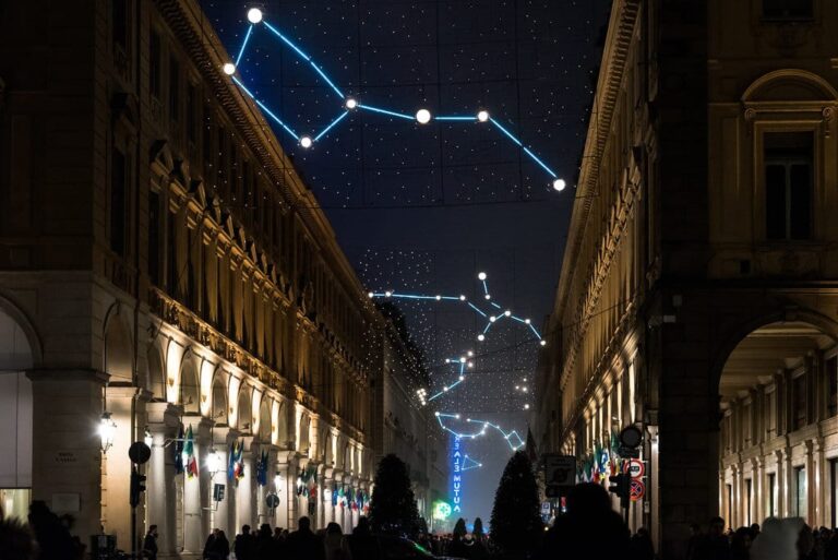 Constellations lumineuses tendues au-dessus de la via Roma, entre les arcades éclairées, la nuit