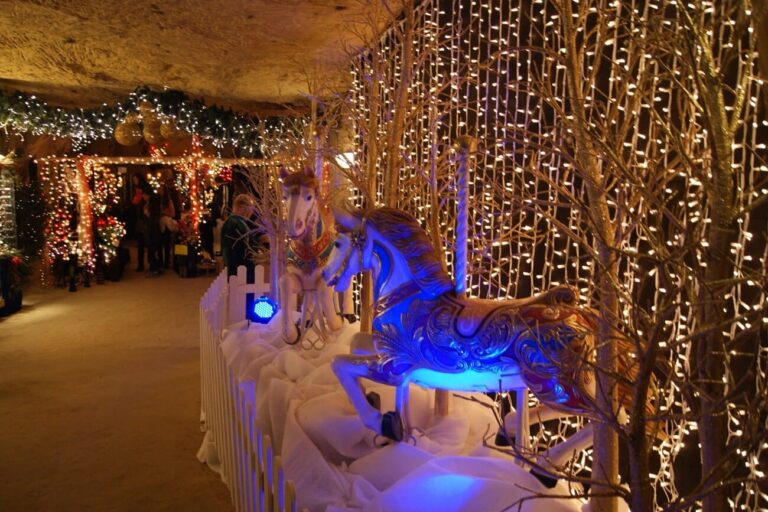Galerie de la Gemeentegrot tapissée de rideaux de lumières, avec un cheval de carrousel illuminé de bleu
