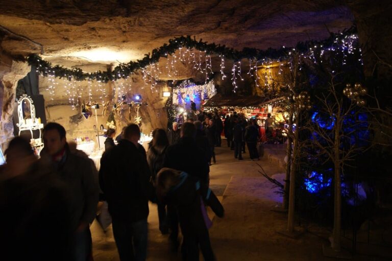 Allée du marché de Noël souterrain de la Gemeentegrot, sous des guirlandes de sapin et de lumières accrochées à la roche