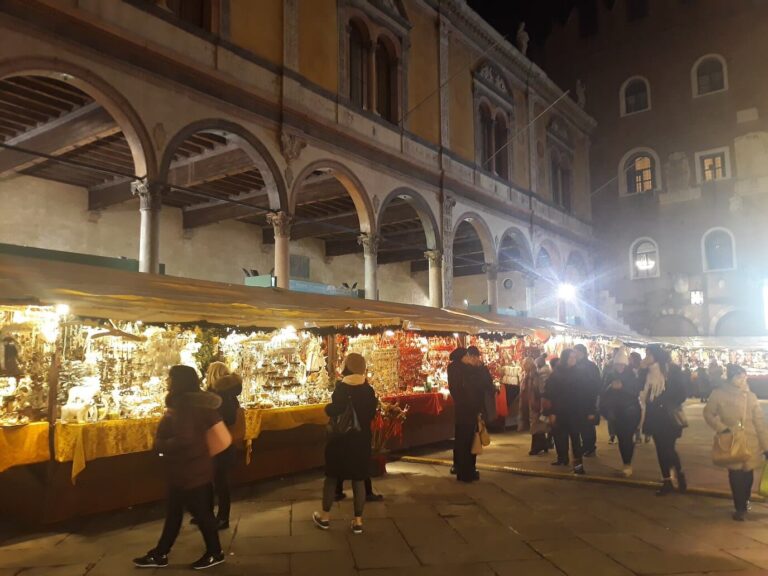Stands éclairés du marché de Noël sous les arcades de la Loggia del Consiglio, la nuit